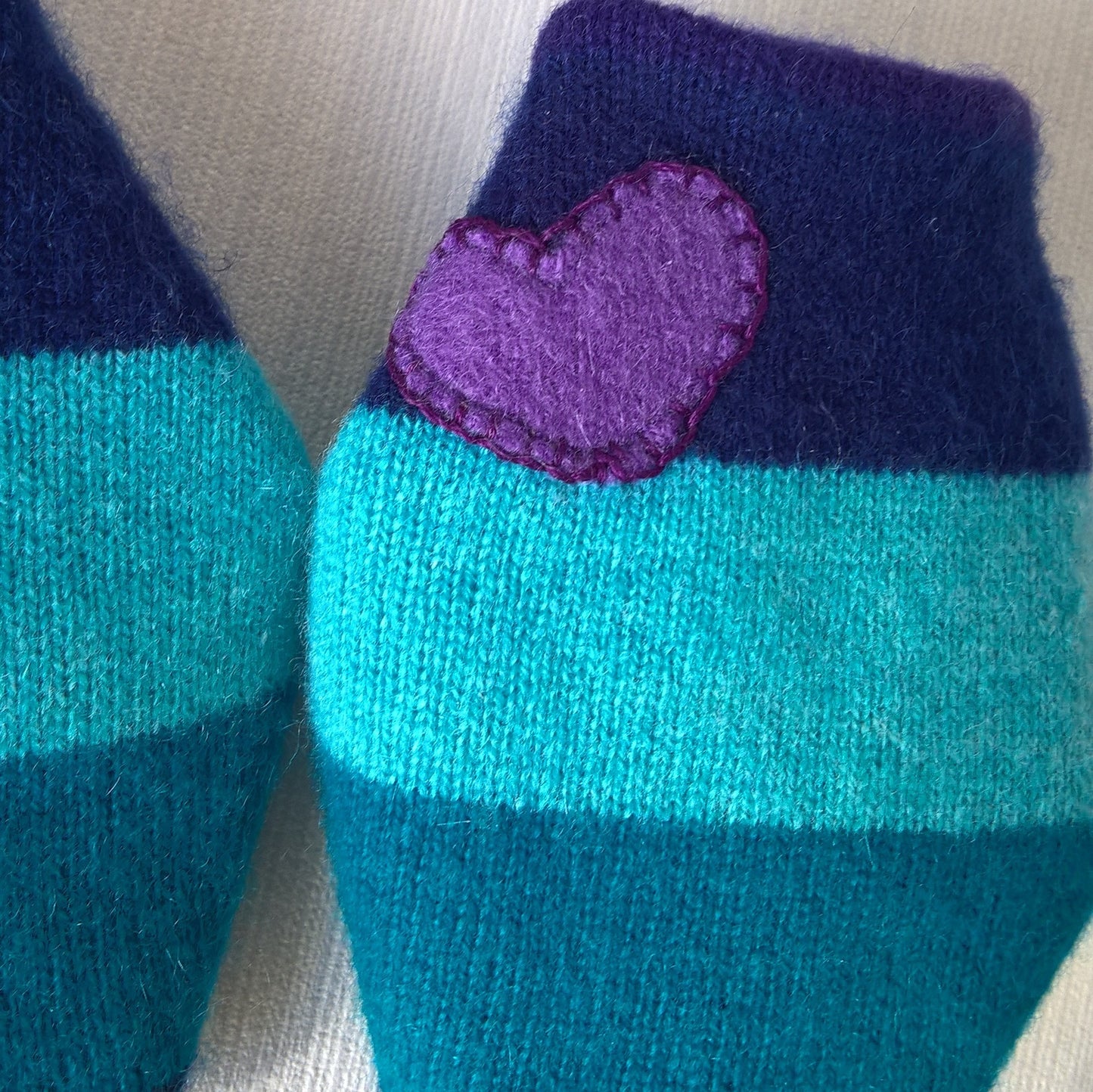 A purple cashmere heart has been appliqued to one wrist cuff
