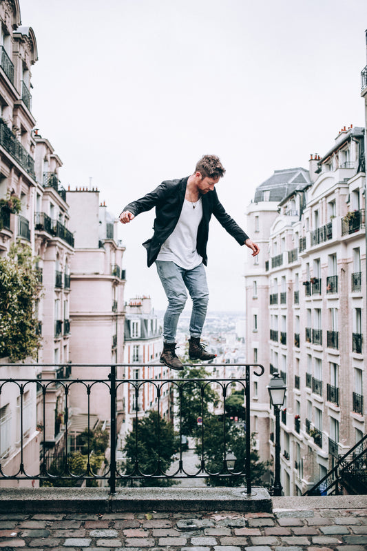 Fashion confident male balancing on a rail above the city