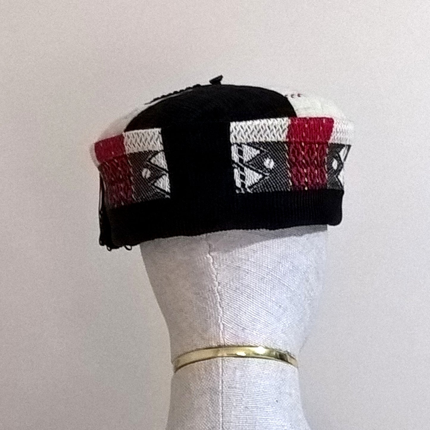 Back view of black, red and cream segment smoking cap