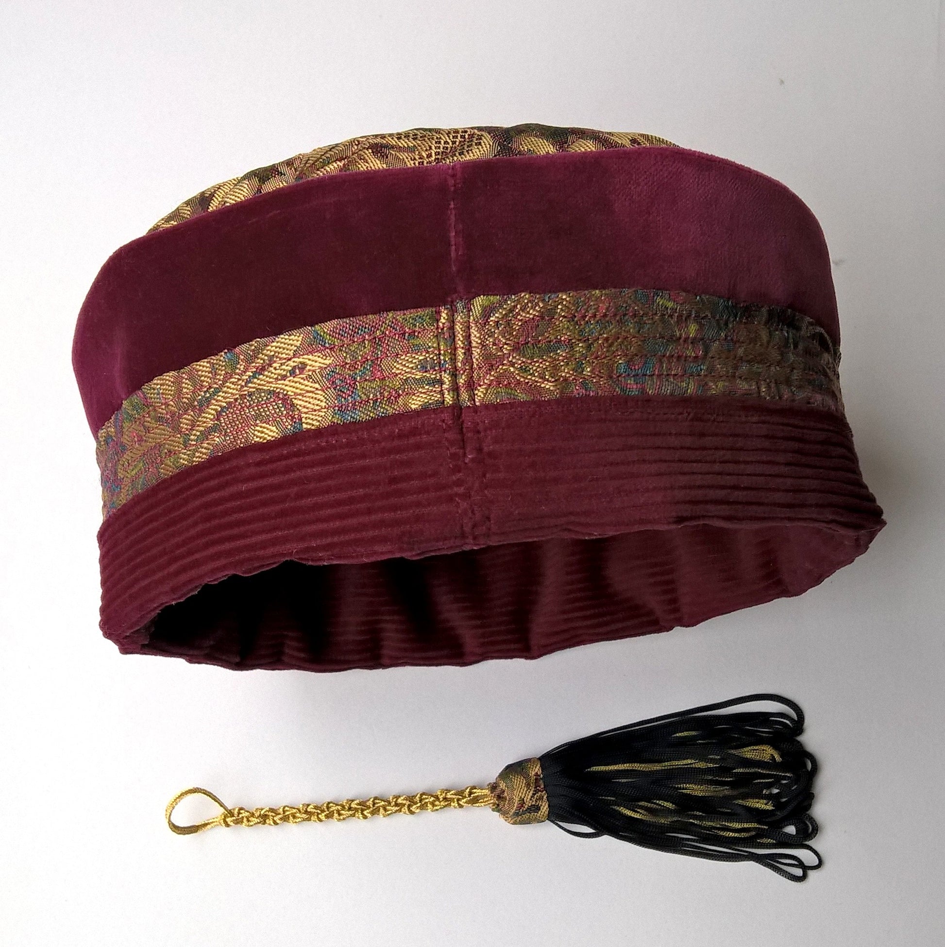 Back view of gold brocade and red velvet smoking cap, showing removable tassel