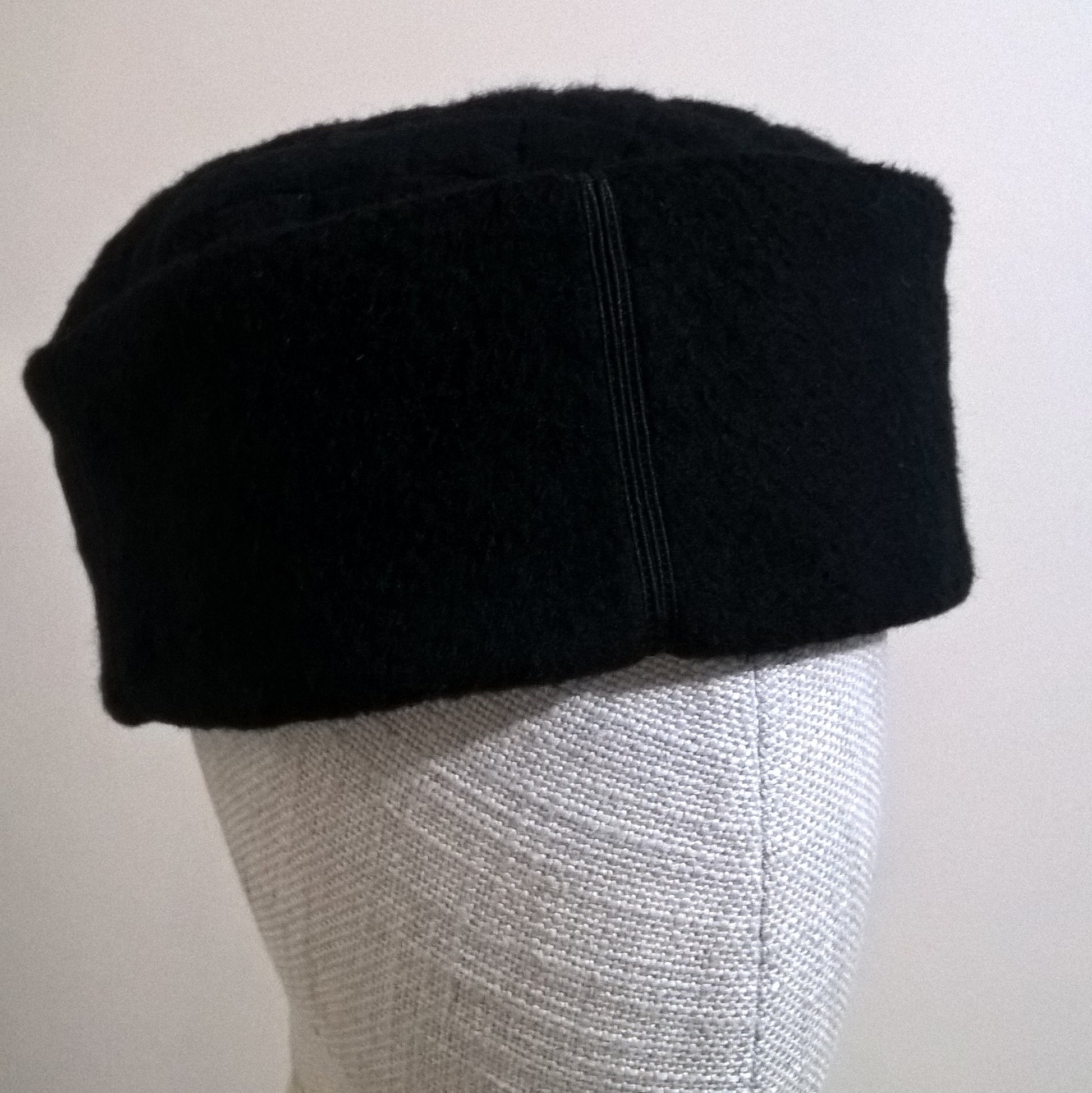 Smart black cashmere skull cap with satin braid and button detail on Crown