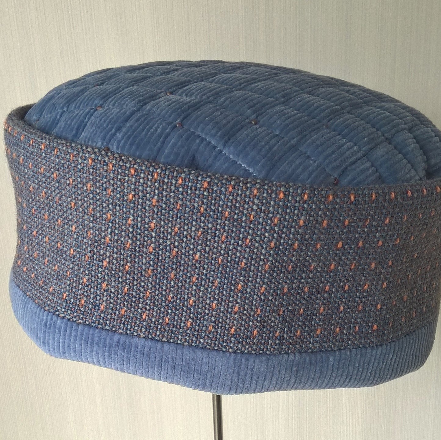 The blue corduroy hat has an ethnic crown with an orange tick pattern