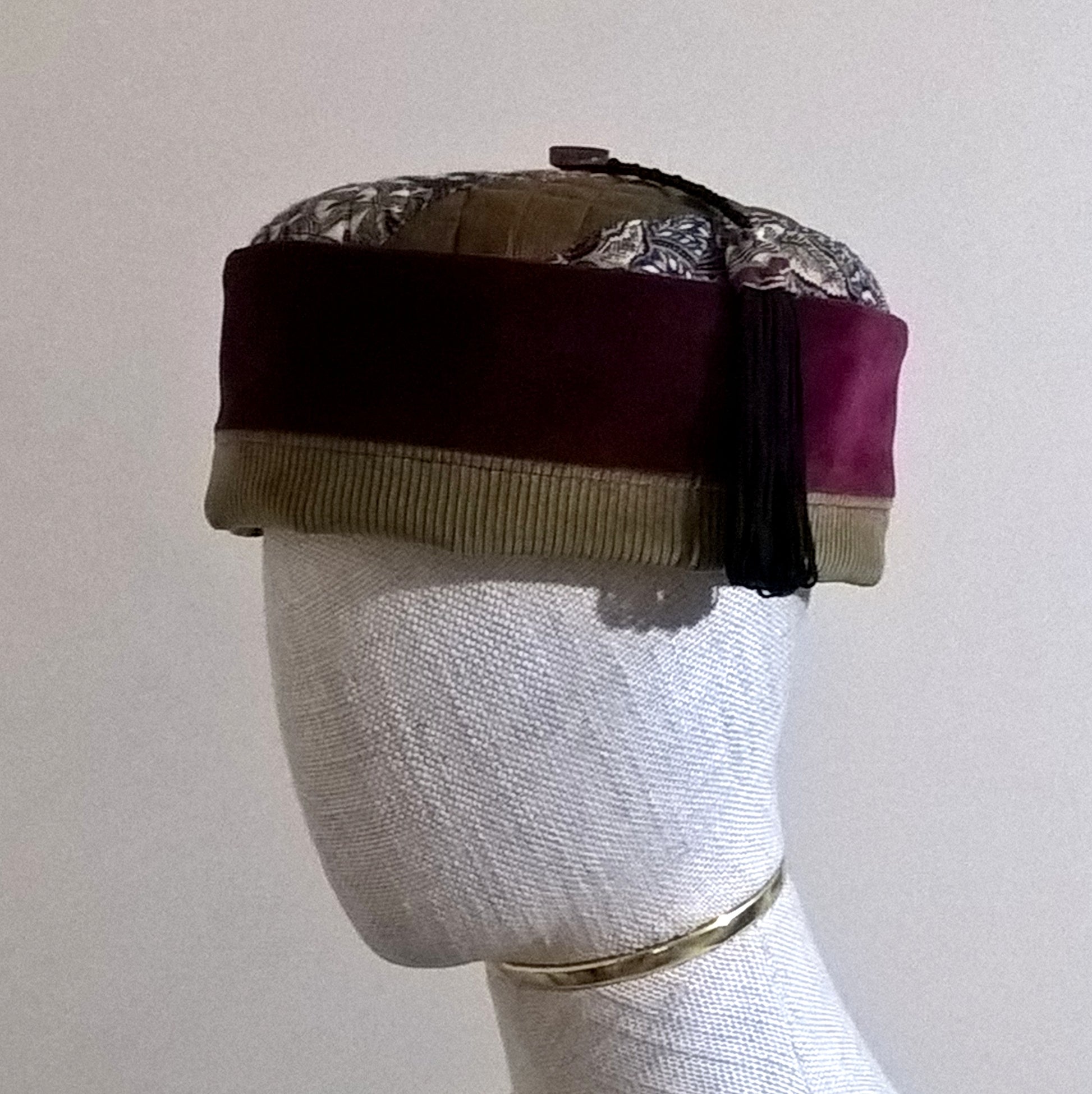 The smoking cap has a burgundy velvet crown edged with olive brown corduroy, quilted tip with paisley applique and a black and paisley macrame tassel