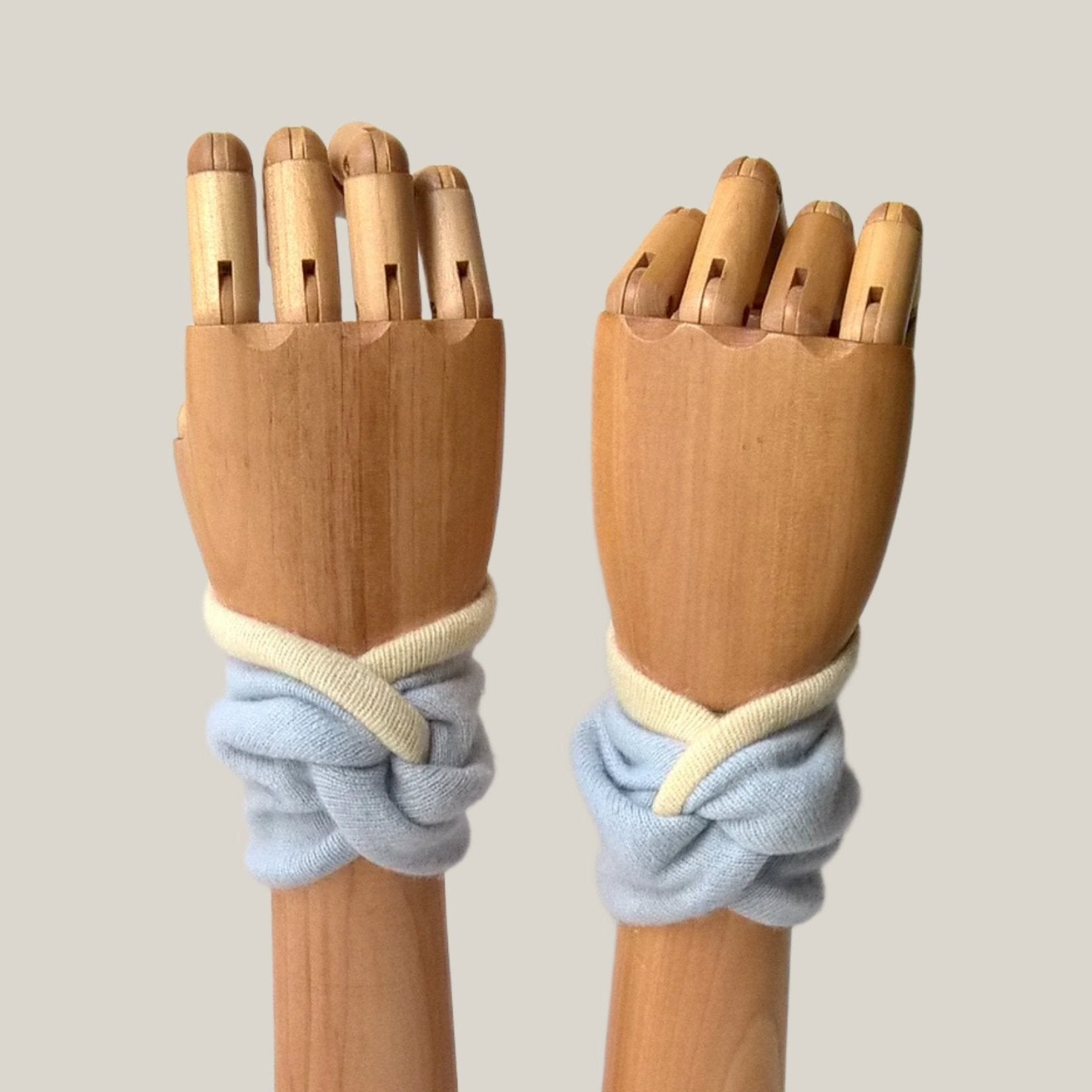 Twisted knot cashmere wrist warmer pulse point cuffs in pale blue and cream.