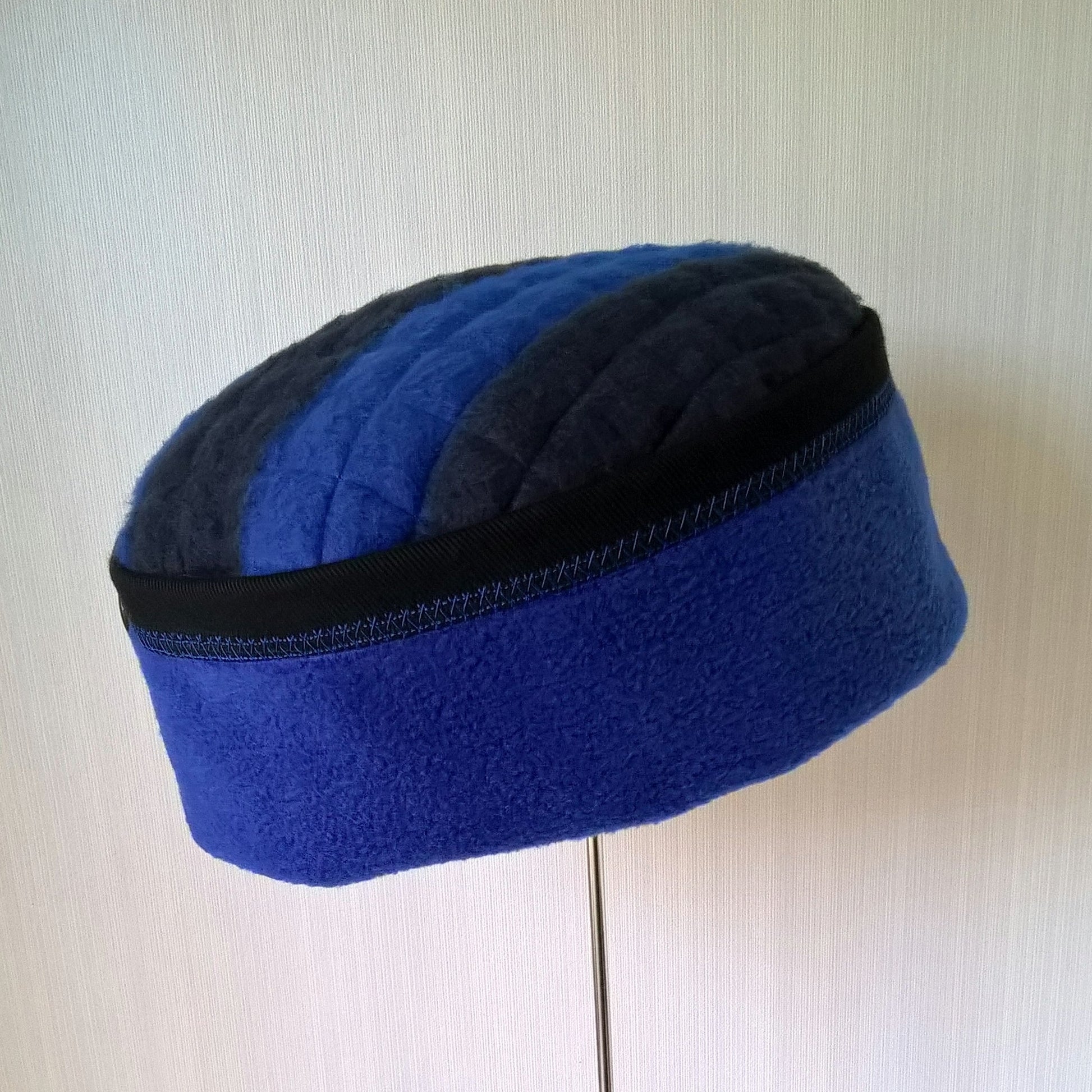 Pillbox shaped fleece hat in cobalt blue with black trim