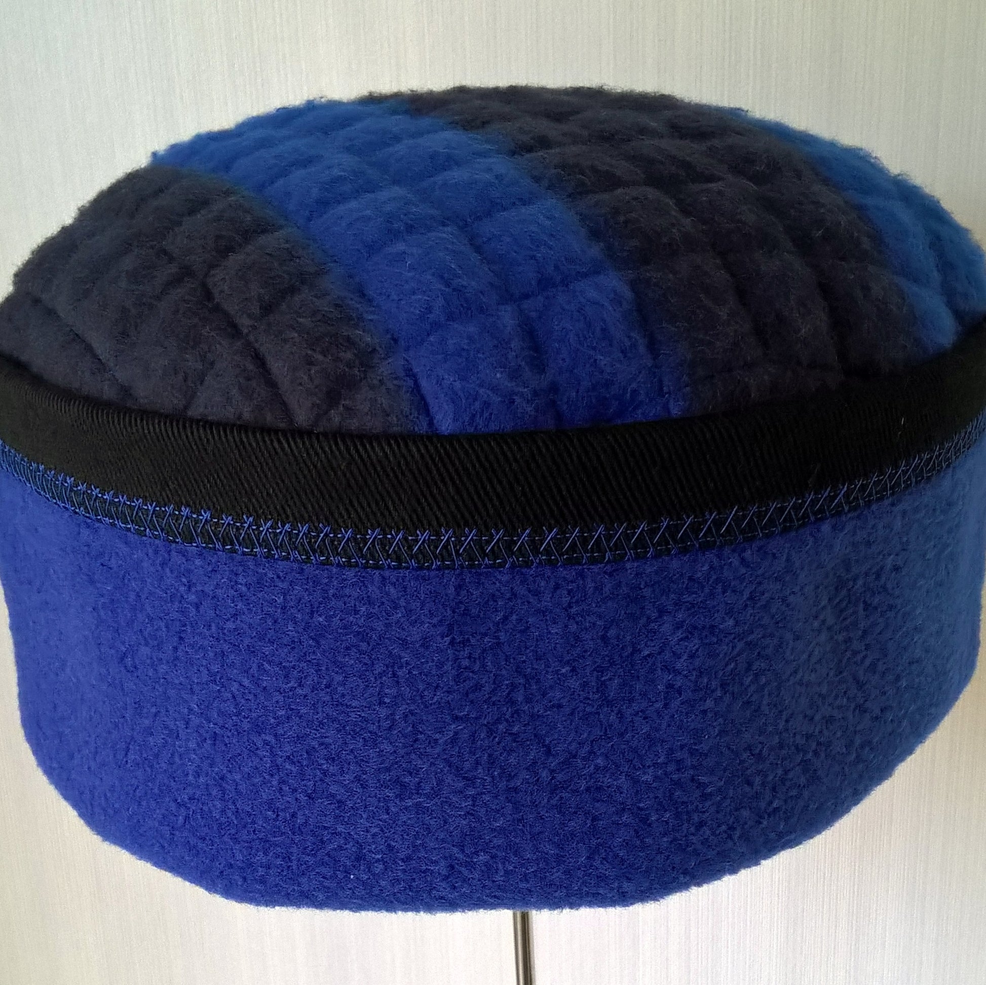 Fleece hat has cobalt blue stitch detail around edge of crown