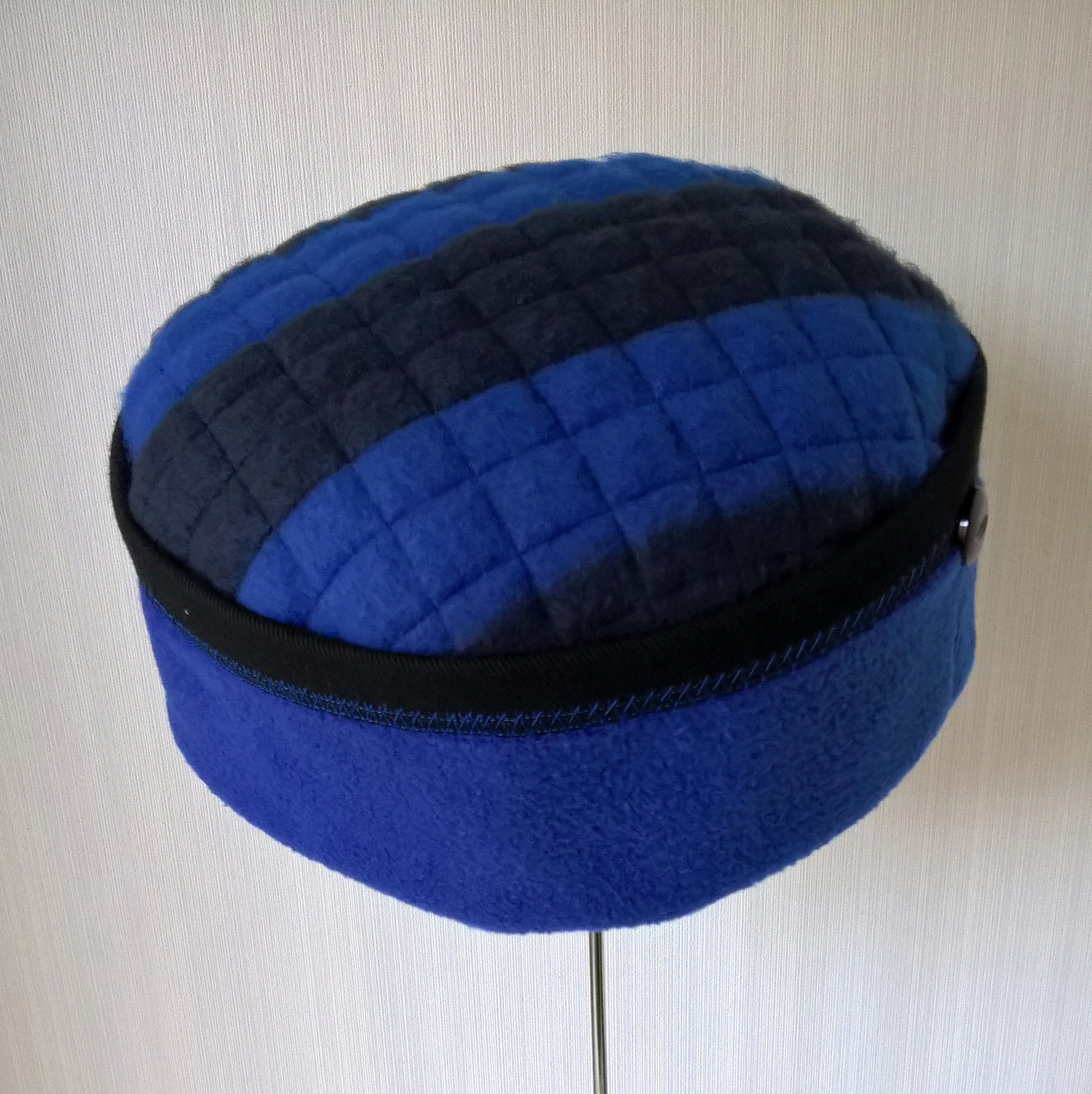 This vibrant cobalt blue hat has black stripes on the tip