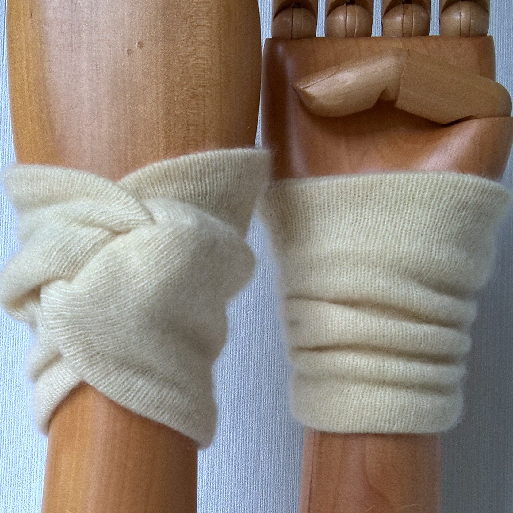 Cream cashmere wrist warmers in a knot design
