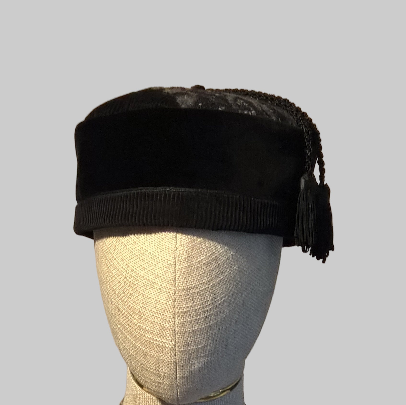 Black velvet and corduroy smoking cap with two tassels on a mannequin head