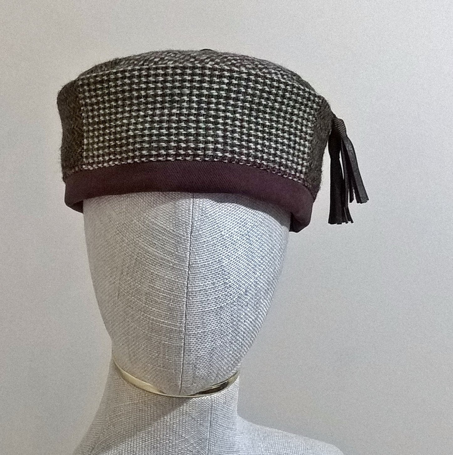 Patchwork Harris Tweed smoking cap with leather tassel in browns, maroon, and cream.