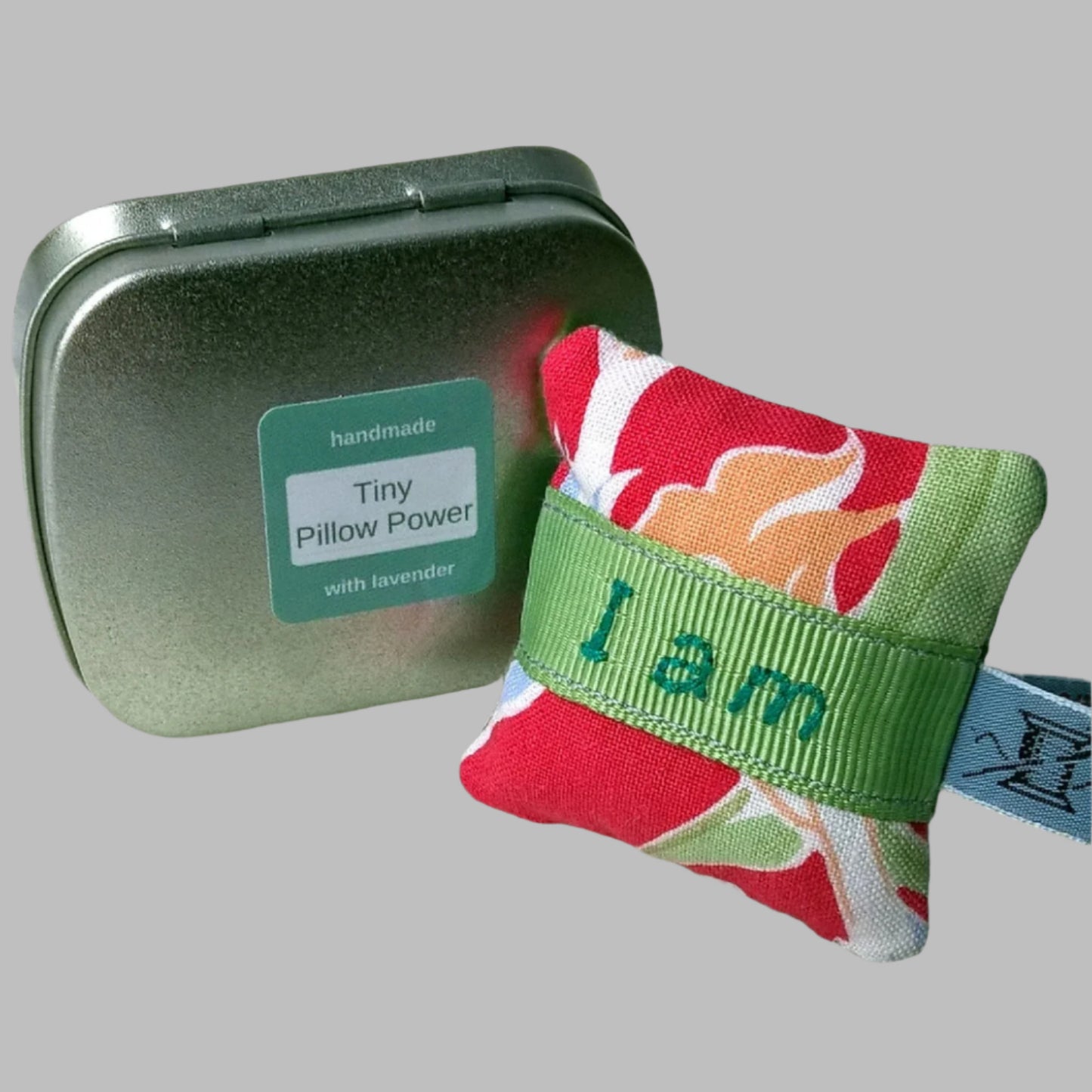 Mini lavender pillow embroidered with inspiring quote I am enough shown next to its small presentation tin