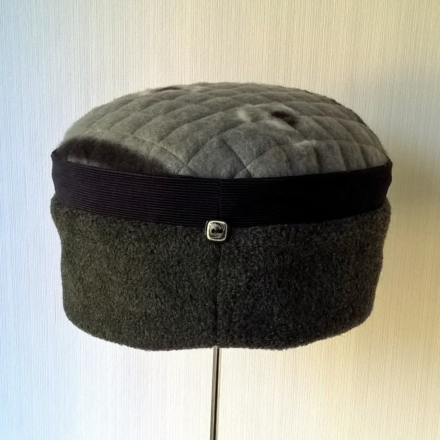 Grey fleece hat with navy corduroy trim and button detail at the back