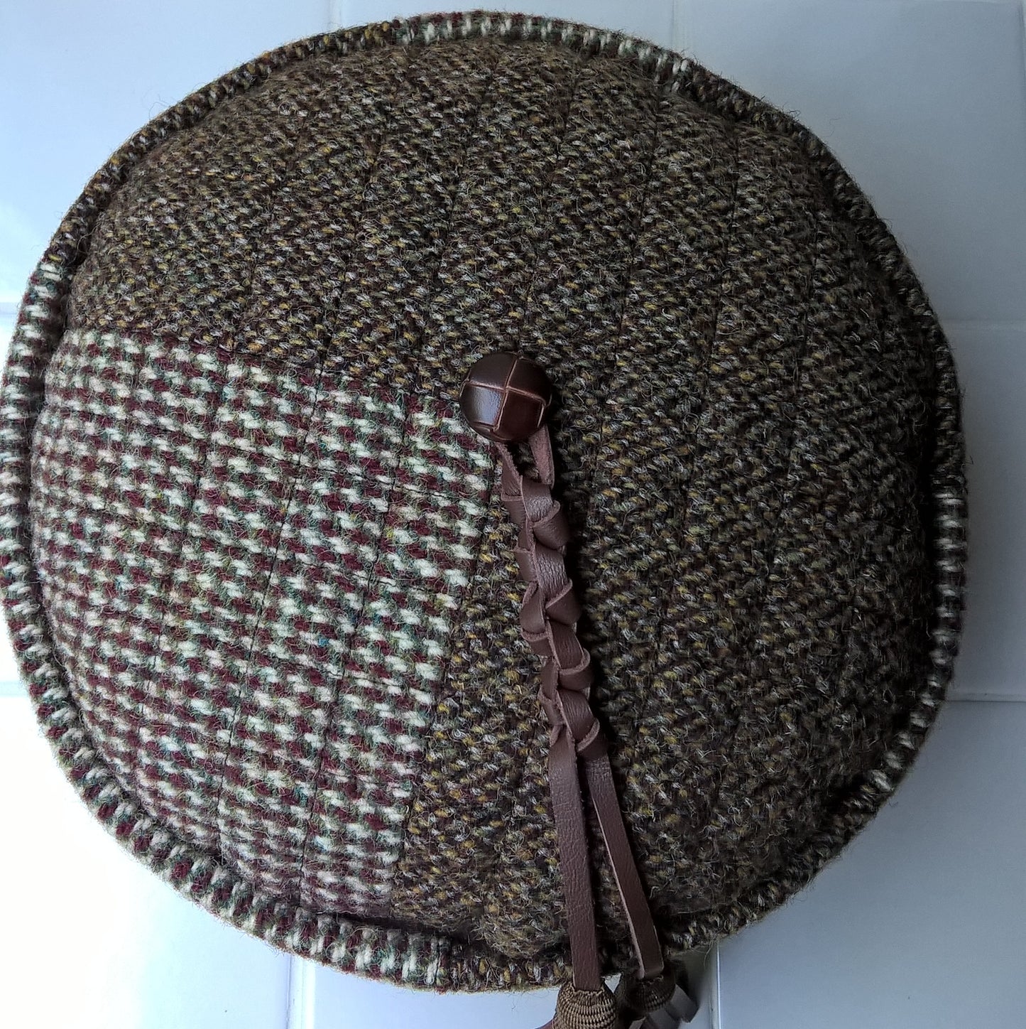 Tip of the Harris Tweed smoking cap with vintsge jacket button and macrame leather tassel