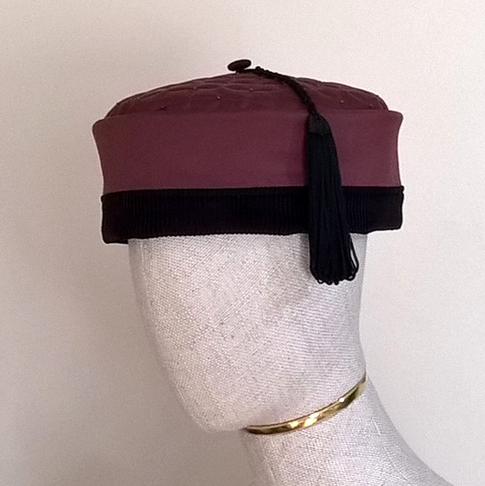 The beautiful maroon smoking cap is given a dramatic look the black corduroy edging and black tassel