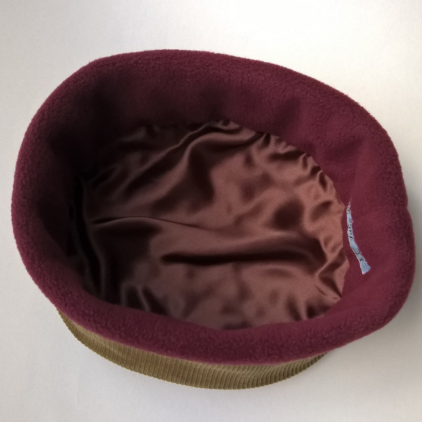 The hat is half lined with burgundy fleece and finished with chocolate brown satin