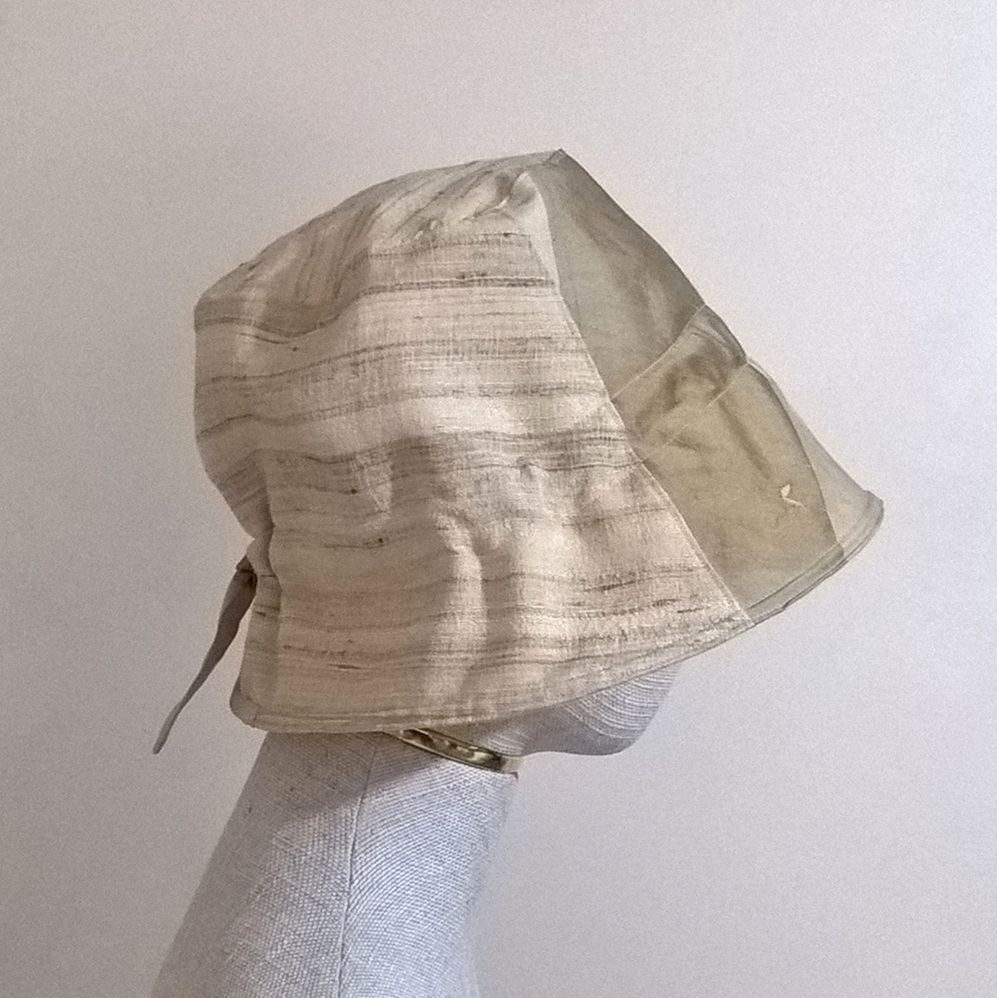 The bell shaped bucket hat has a bonnet style adjustable tie ribbon back
