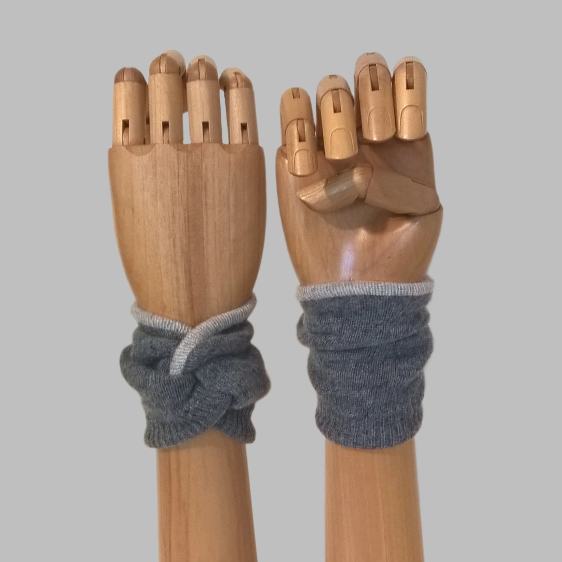 Wrist warmer cuffs handmade in a knot design, dark grey pure cashmere edged and lined with pale grey cashmere