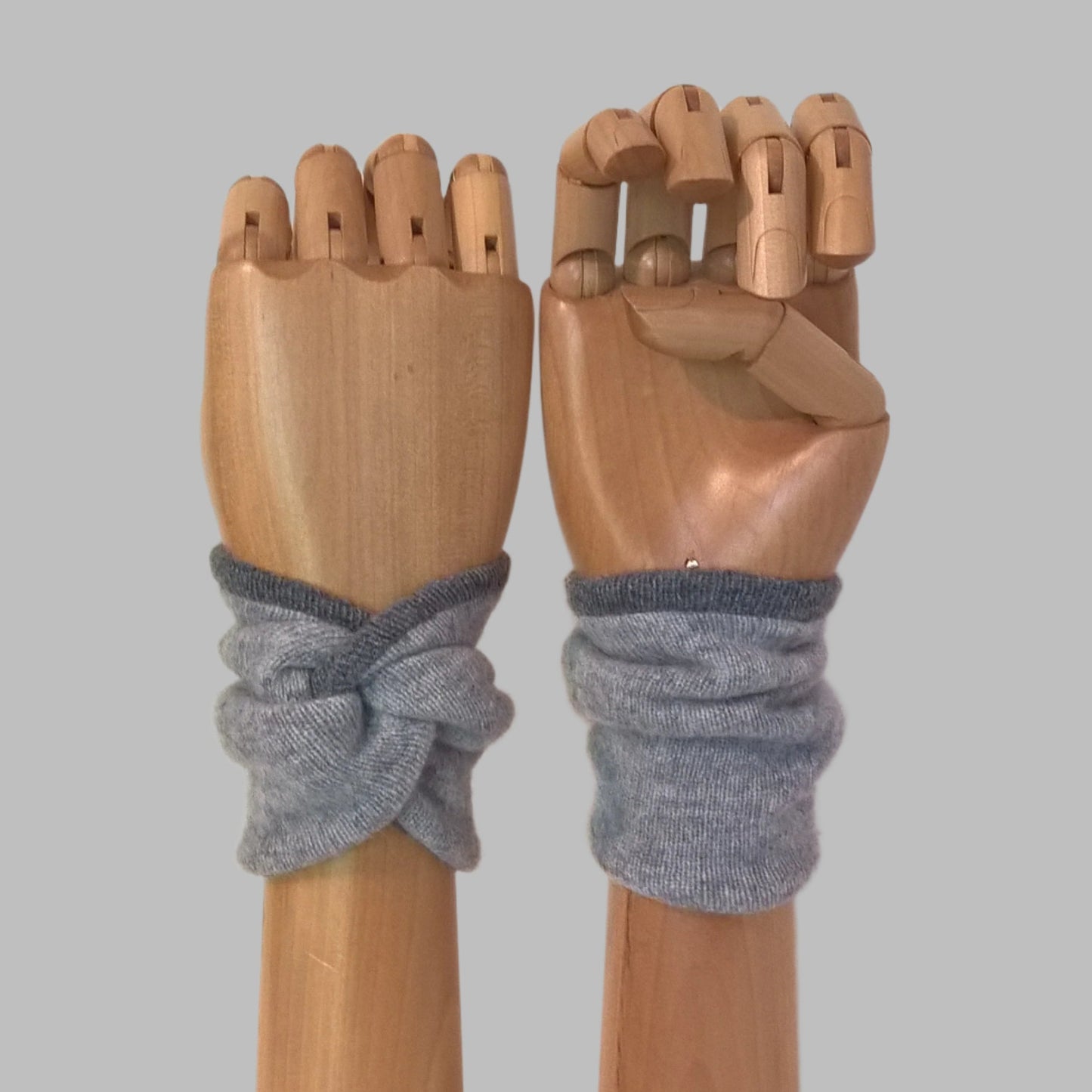 Light grey pure cashmere wrist warmer cuffs, handmade in a knot design, edged and lined with dark grey cashmere