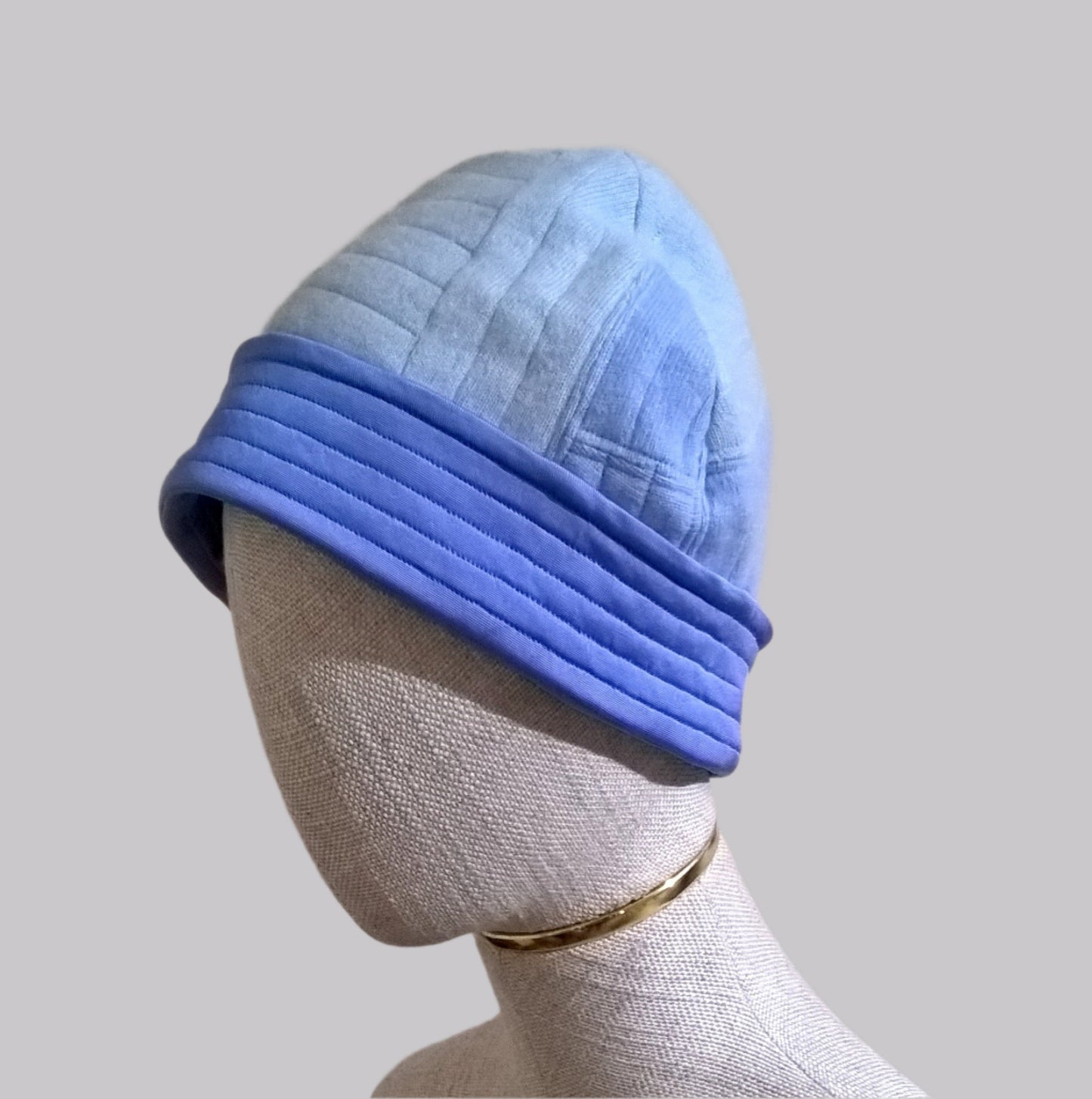 Side view of patchwork cashmere beanie hat with silk cuff in shades of blue