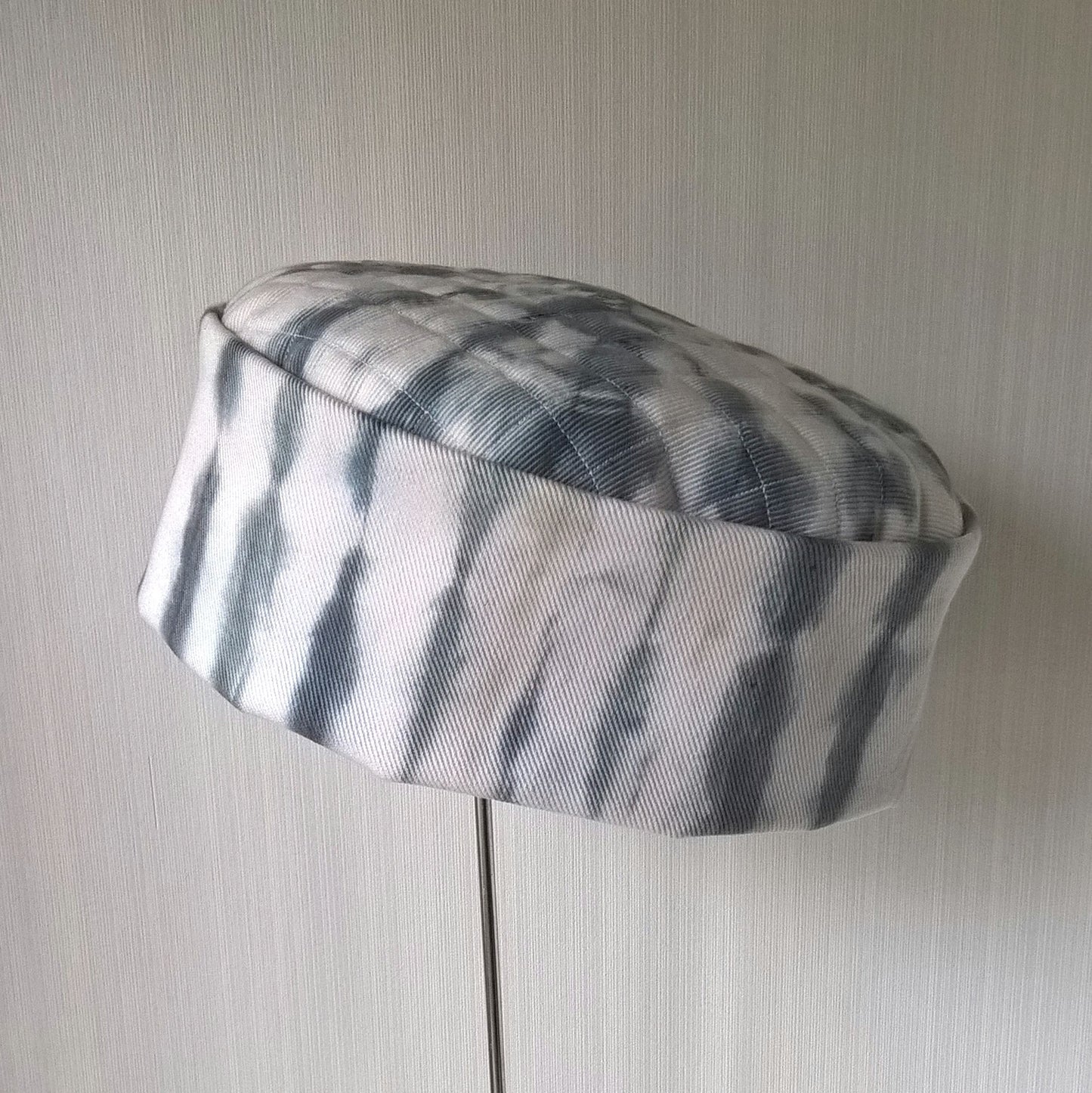 White pillbox shaped cap with black shibori tie dye