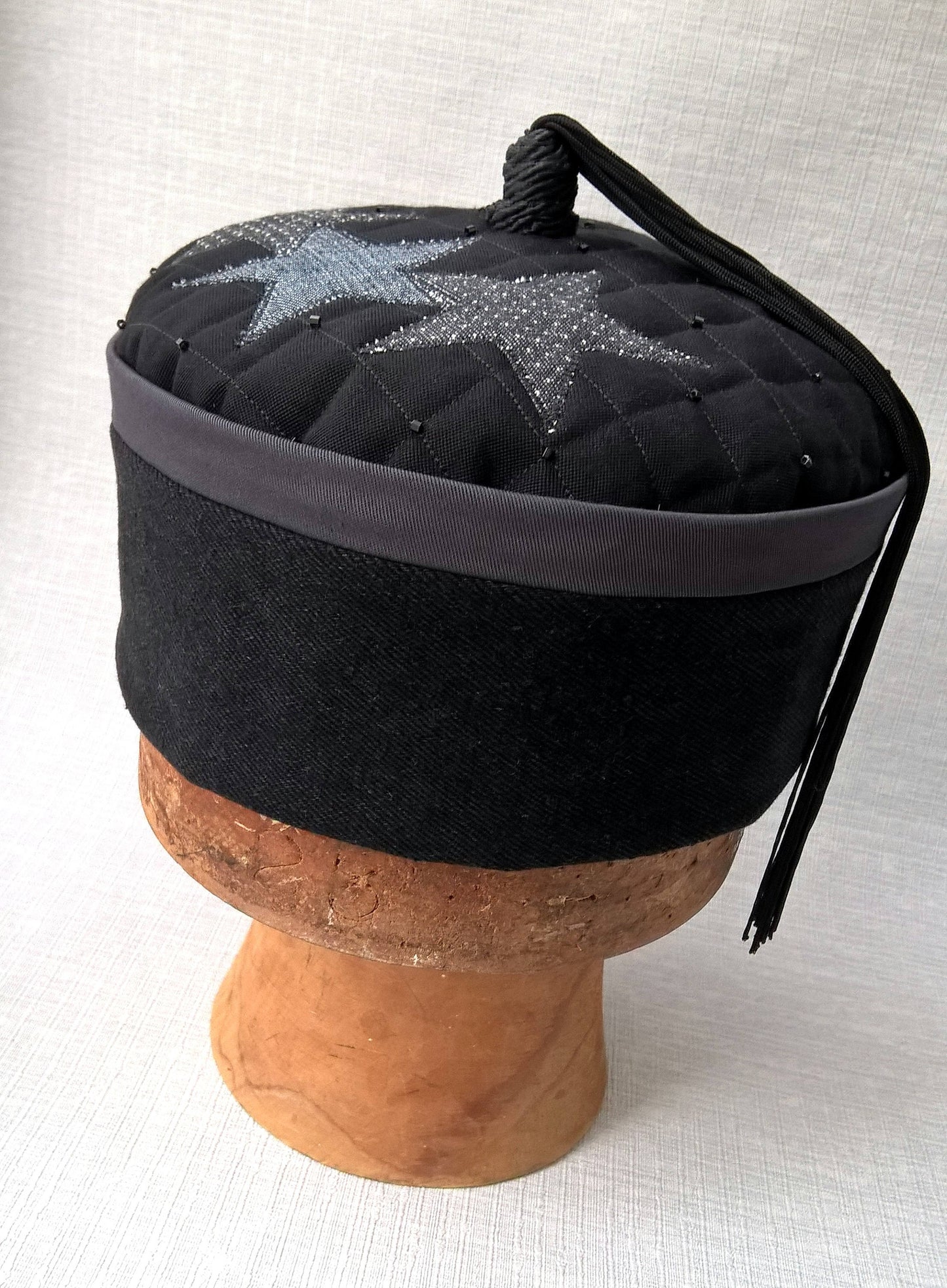 Front view of wizards tassel smoking cap in black and grey with applique stars