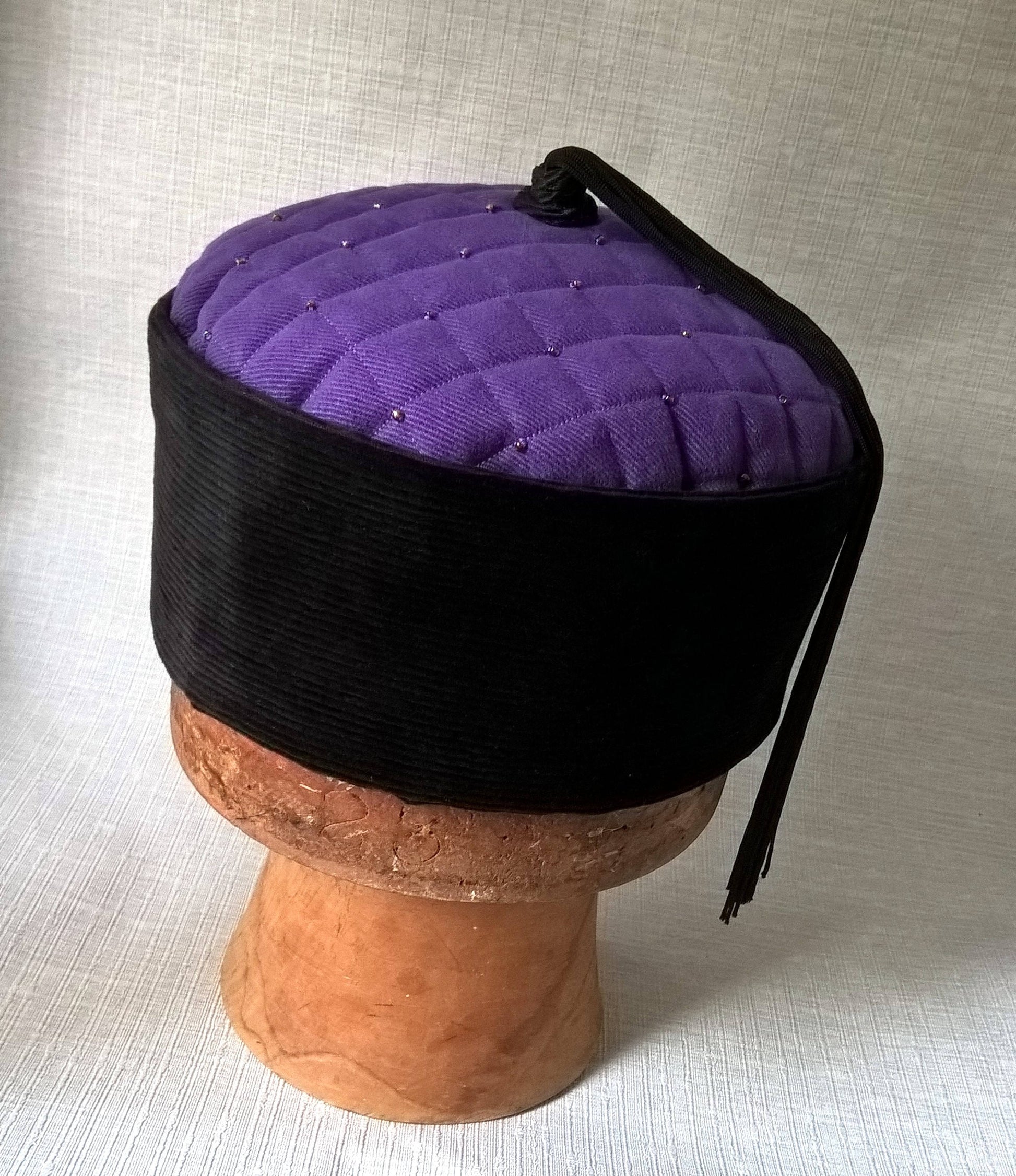 The purple lounge cap has a jet black corduroy crown
